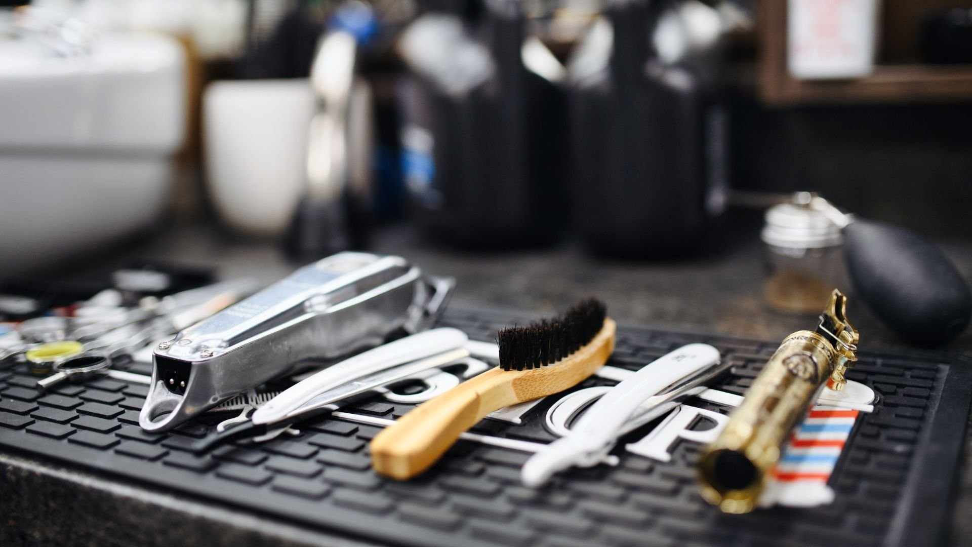 Barbering tools and equipment laid out on a textured black surface