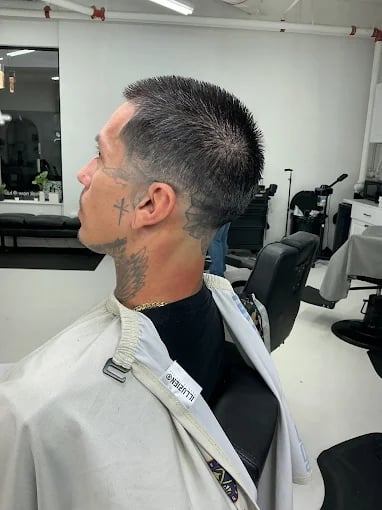 Man with neck tattoo getting haircut in modern barbershop