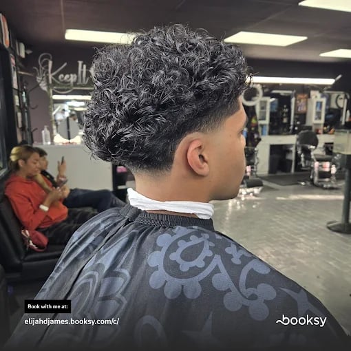 Curly hair fade haircut in a barbershop, viewed from behind