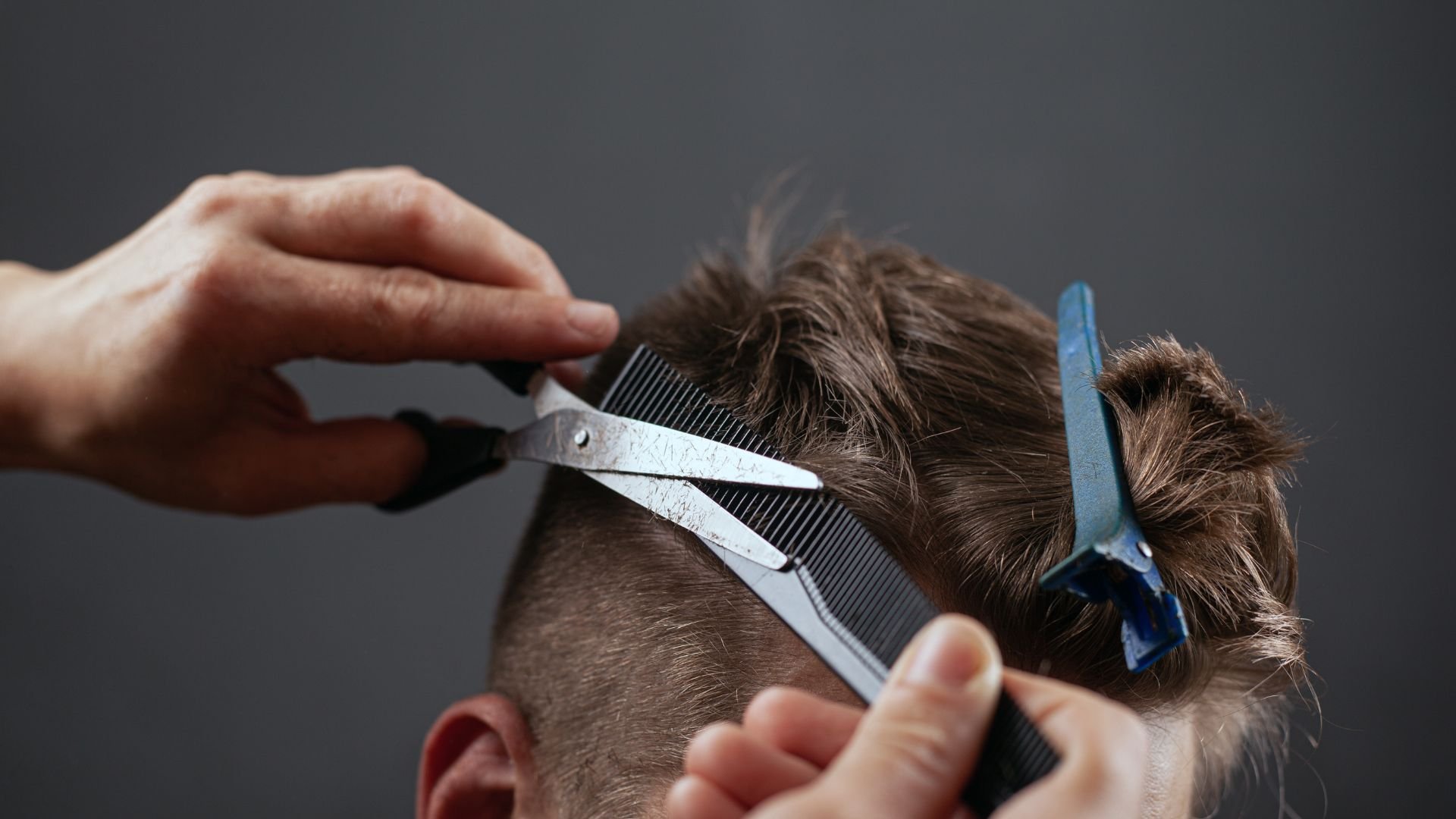 Hairdresser cutting hair with scissors and comb, close-up view