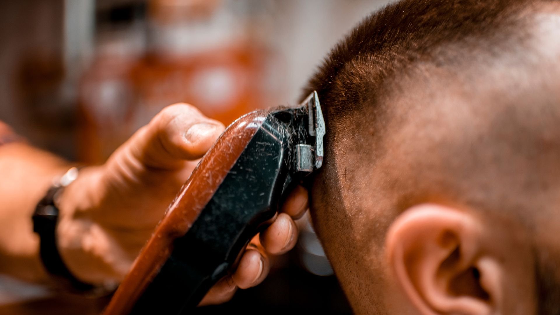 Barber using electric clippers to trim short hair at barbershop