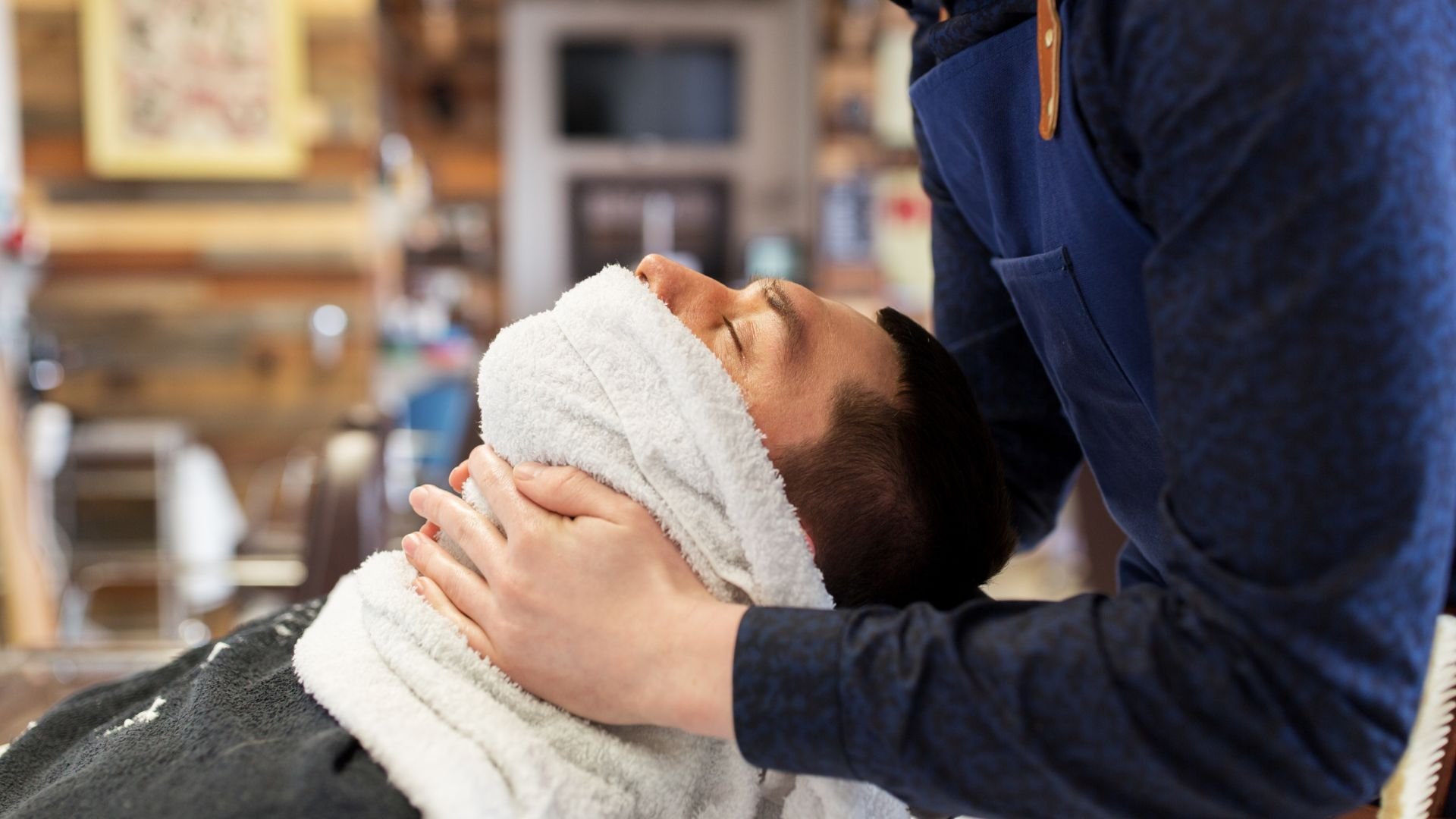 Client relaxing with hot towel during professional barbershop grooming service